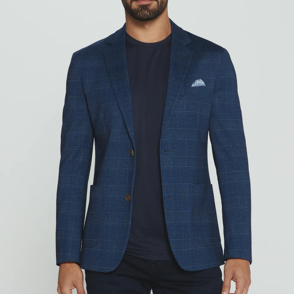 Man wearing a blue checkered blazer over a dark shirt on a white background
