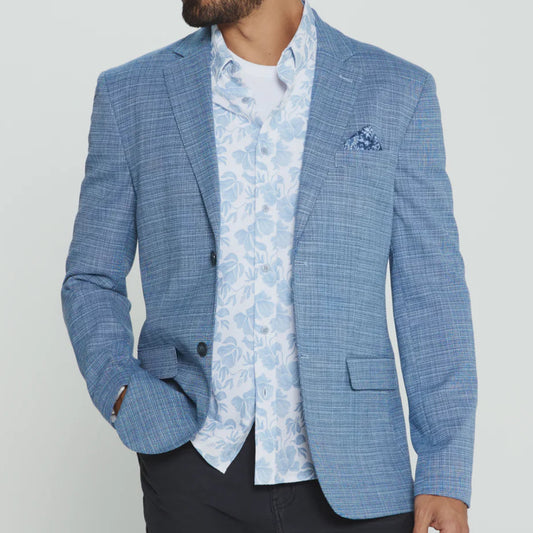 Man wearing a blue checkered blazer over a patterned shirt on a light gray background