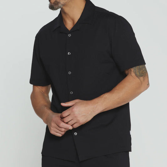Man wearing a black short-sleeve shirt against a plain background