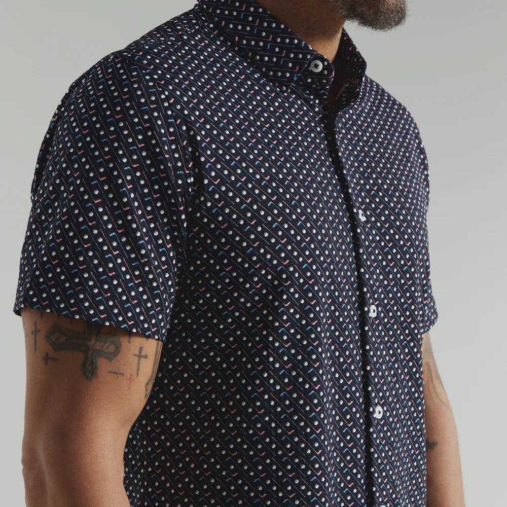 Man wearing a navy short-sleeve shirt with white pattern against a neutral background