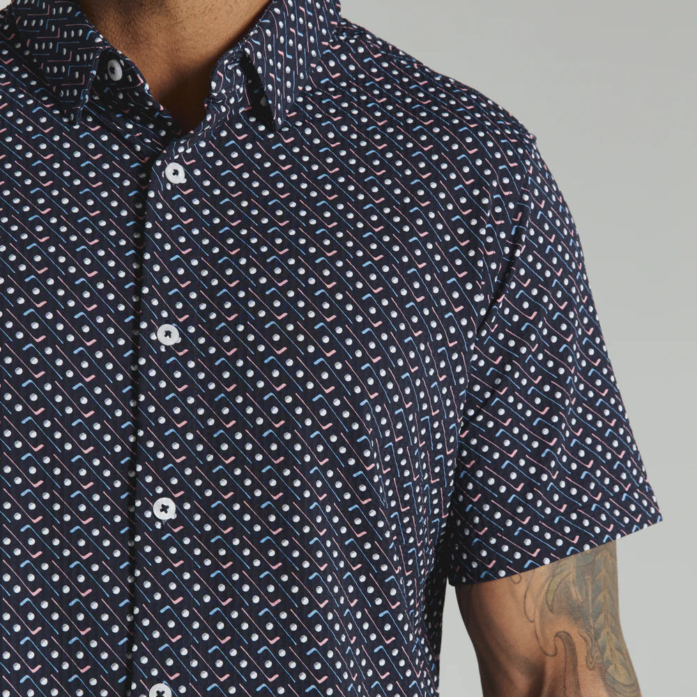 Man wearing a navy patterned short-sleeve shirt against a gray background