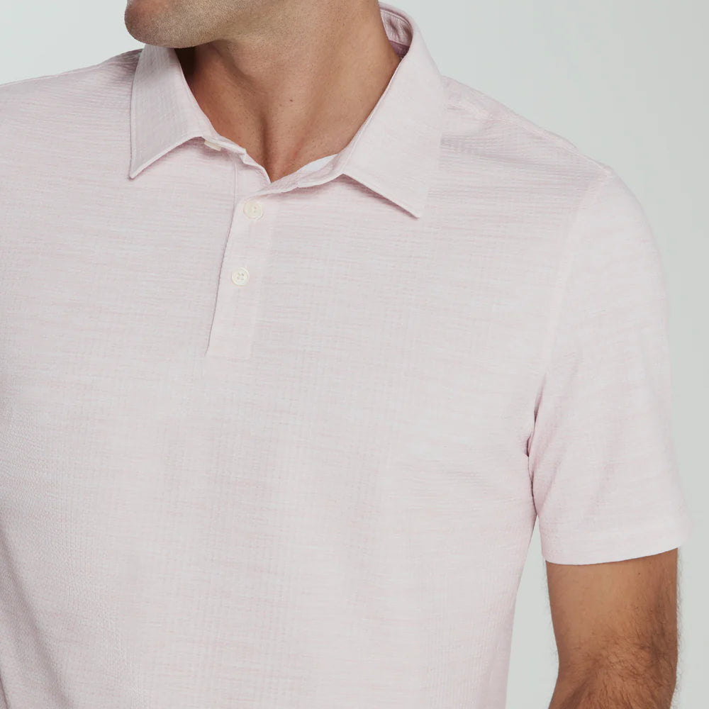 Man wearing a light pink polo shirt against a plain background