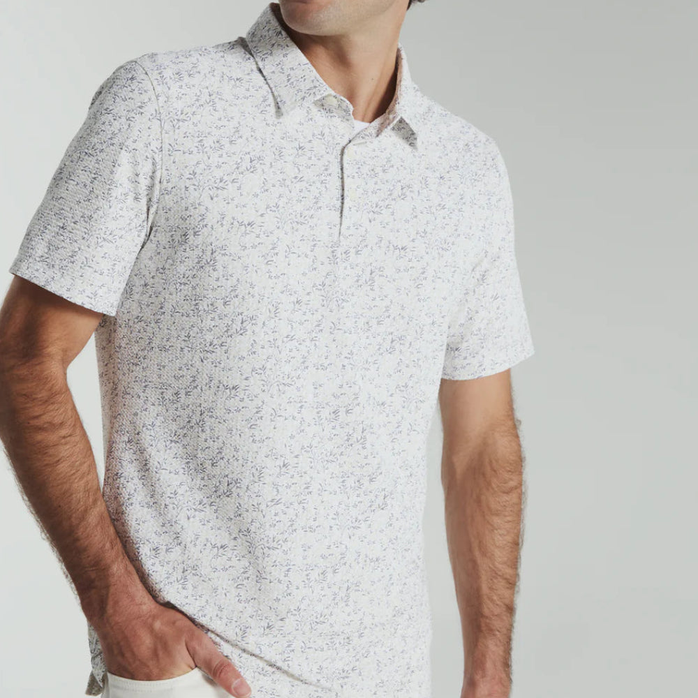 Man wearing a light gray patterned polo shirt against a plain background